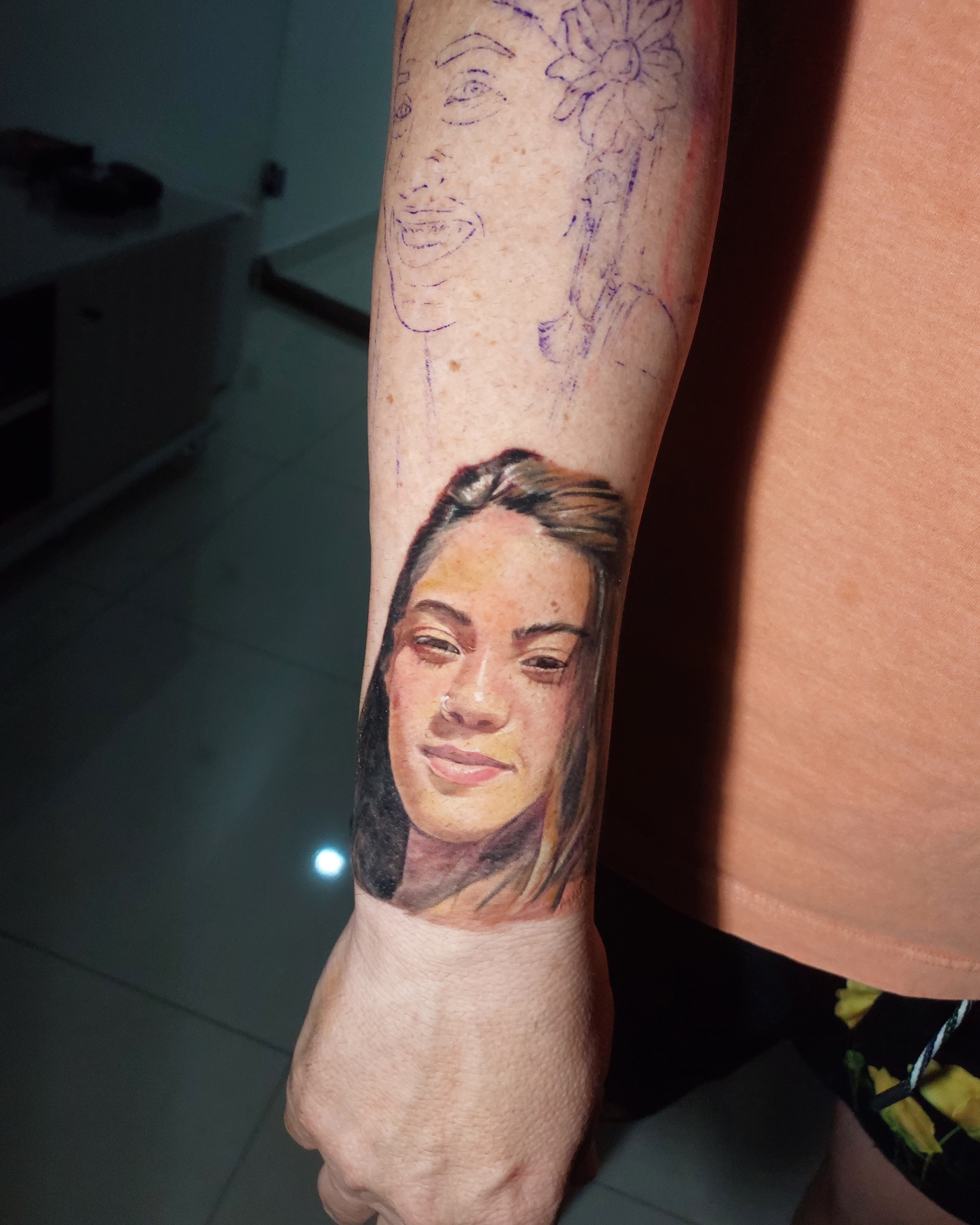 Retrato realista colorido de jovem mulher no antebraço com stencil de referência visível acima